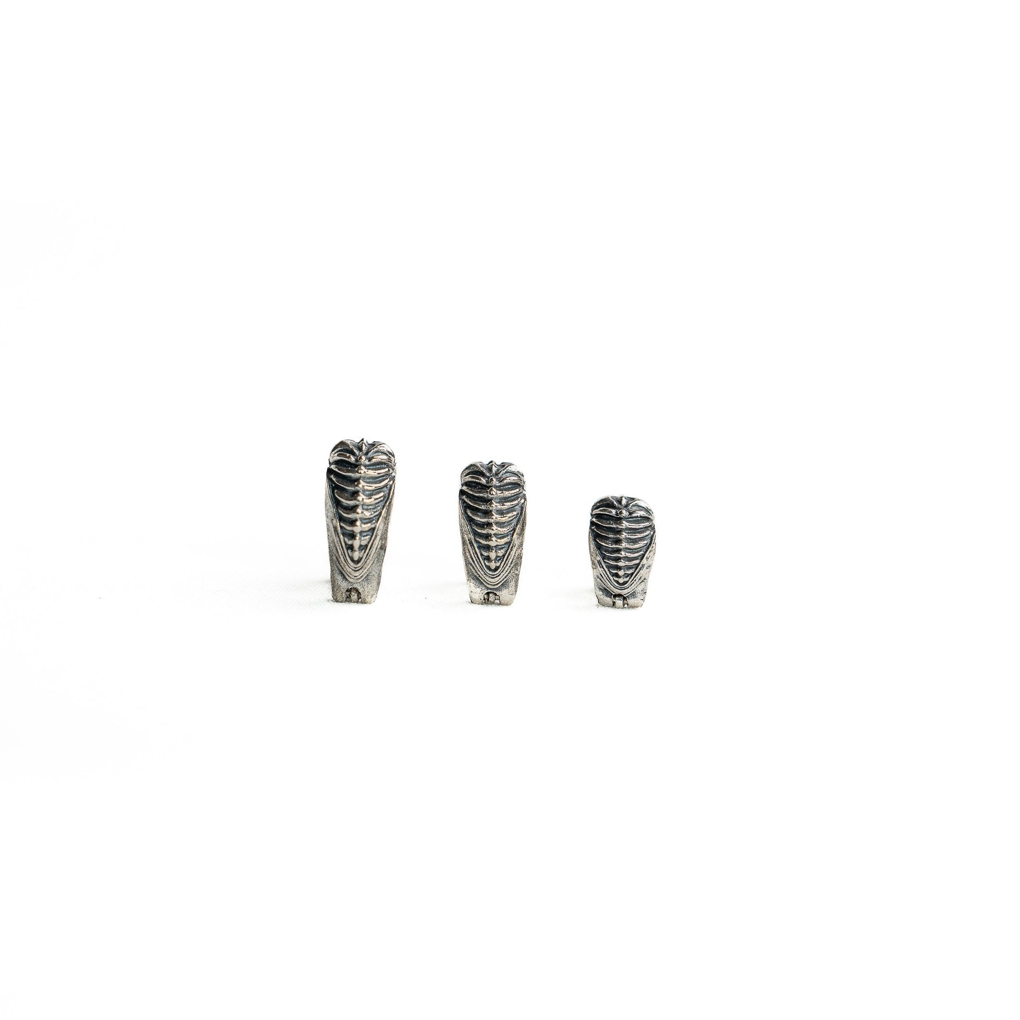 A set of three silver septum clickers, showcasing their unique shape and detailing from a different perspective, emphasizing the bioorganic and cyberpunk aesthetic.